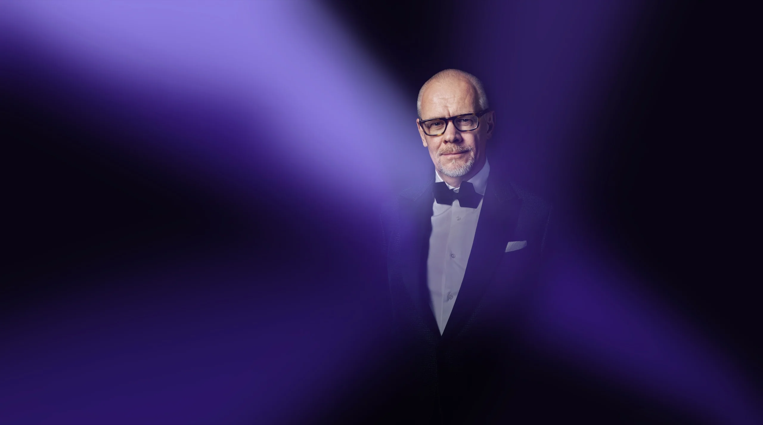 Brand portrait of a MAGUS executive in a tuxedo under purple lighting