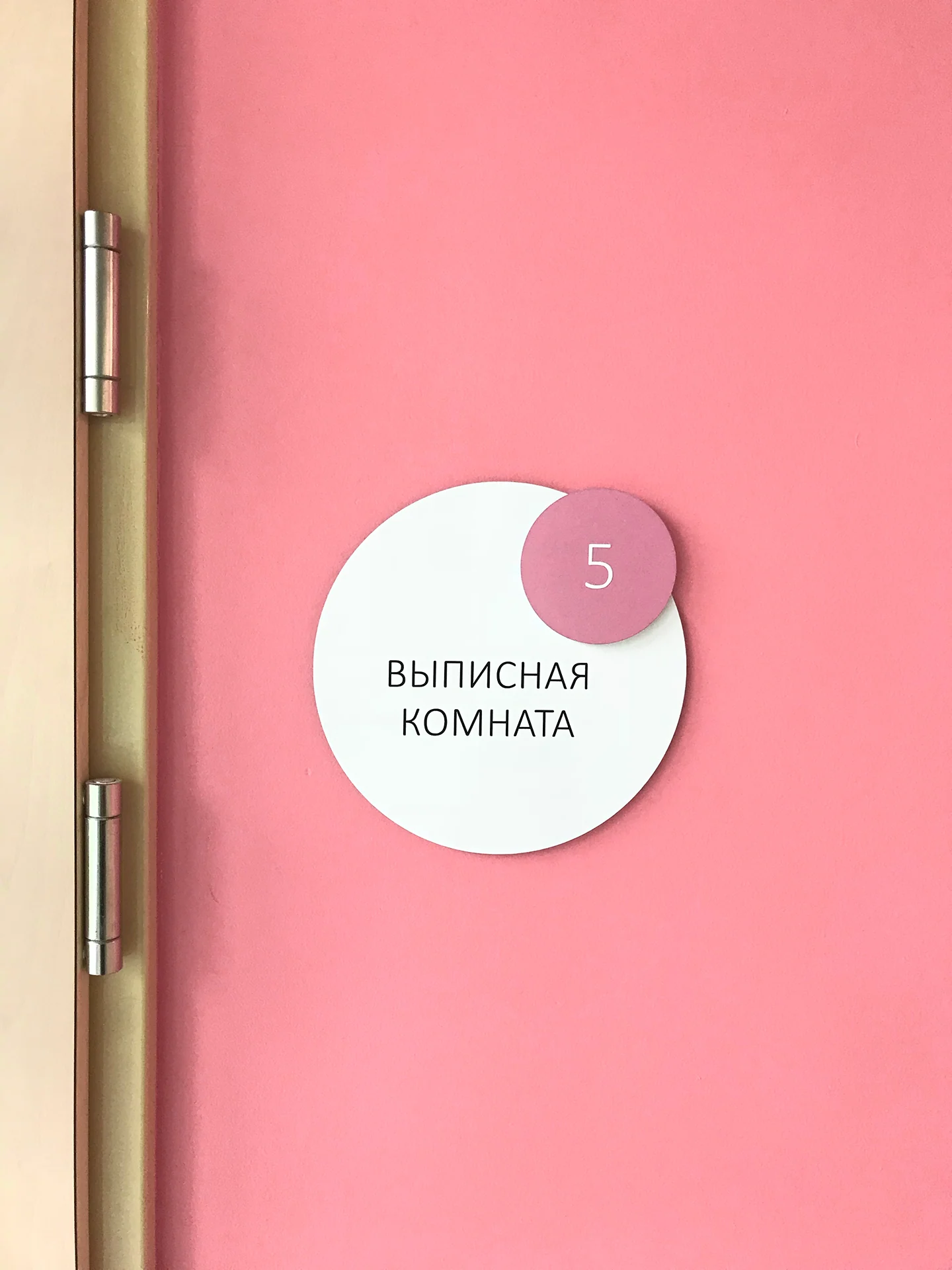 Round “Discharge Room” sign on a pink wall