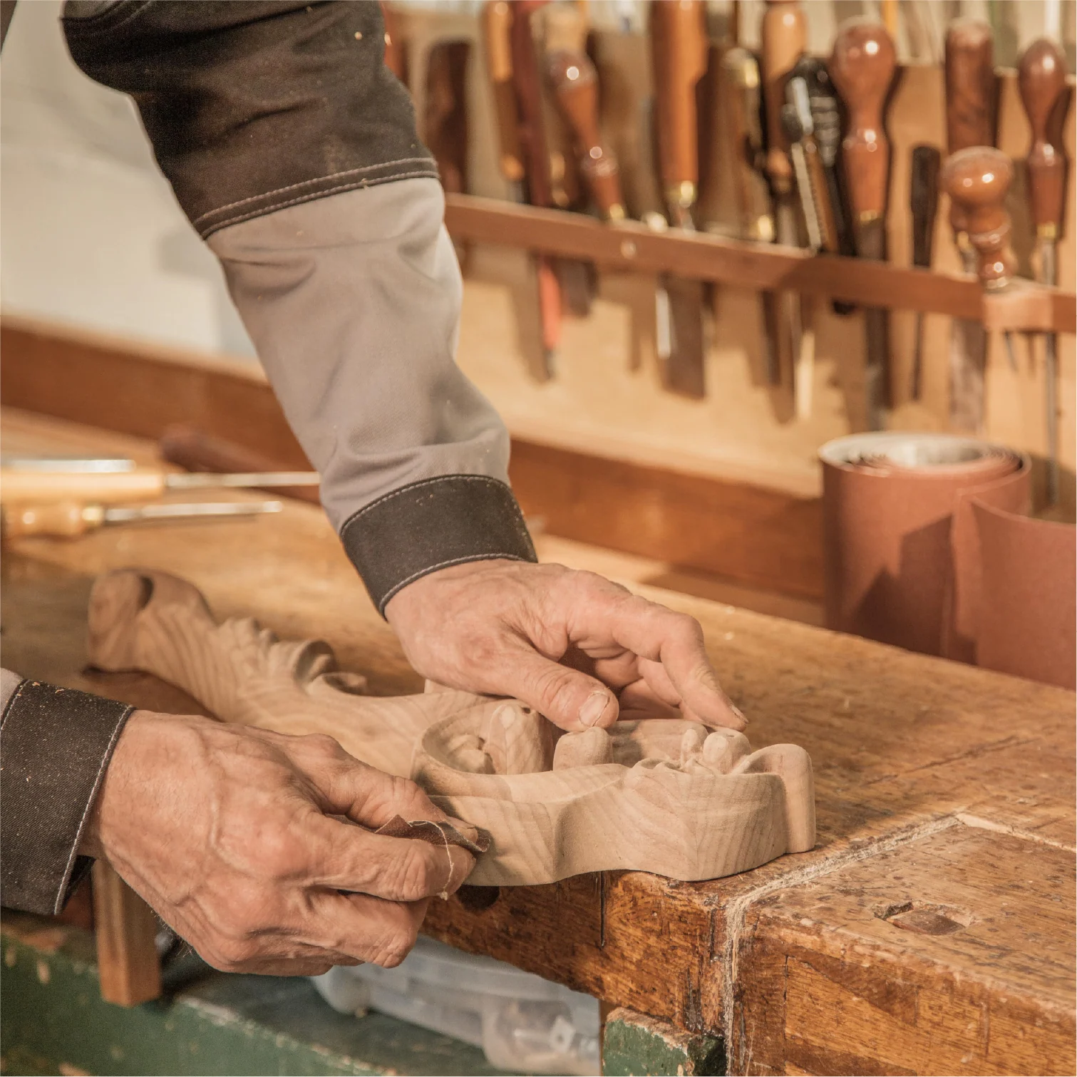 Craftsperson sanding a carved wooden part by hand